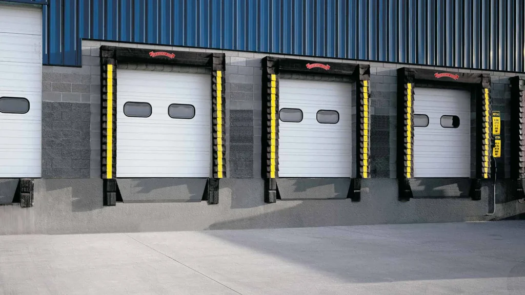 Commercial loading dock with three overhead doors featuring safety bumpers, designed for efficient cargo handling and warehouse operations.
