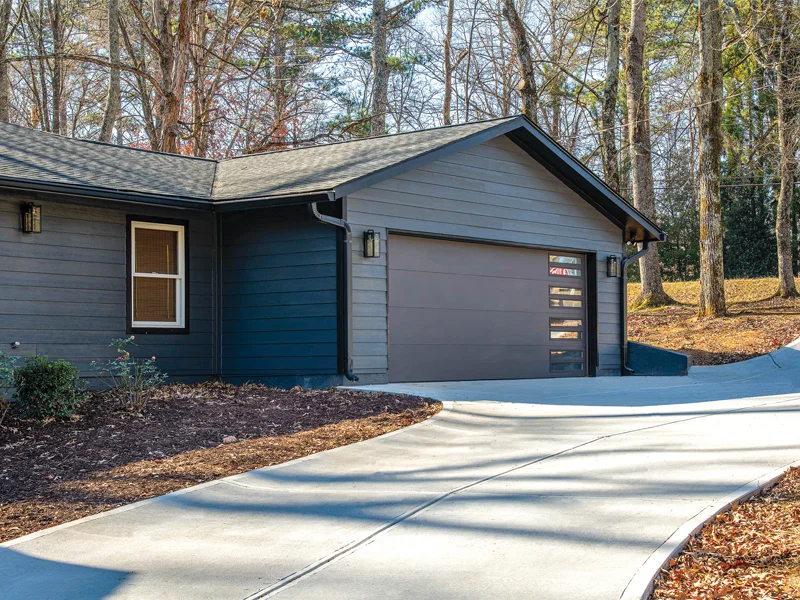 Modern garage door on a residential property in Thousand Palms, CA, surrounded by trees and landscaping, showcasing professional installation and design.