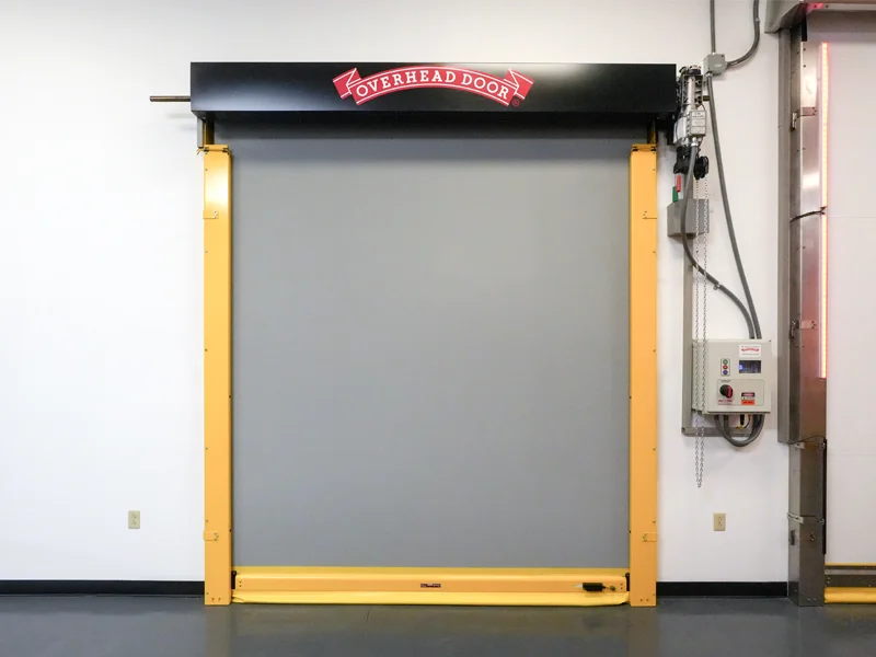 Overhead Door high-speed commercial door with yellow frame and control panel, designed for durability and efficiency in business environments.