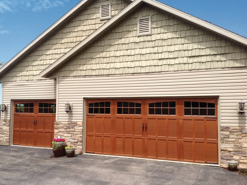 Residential garage with two wooden overhead doors, stone accents, and decorative lighting, showcasing quality garage door solutions by Overhead Door Company of The Desert™.