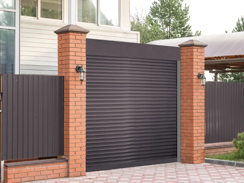 Garage door with modern design, brick pillars, and security lighting, representing garage safety and security practices.