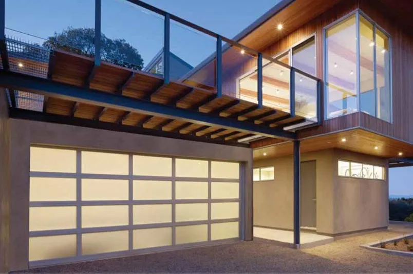 Modern aluminum garage door with sleek design and glass panels, illuminated in evening light, complementing a contemporary home aesthetic.