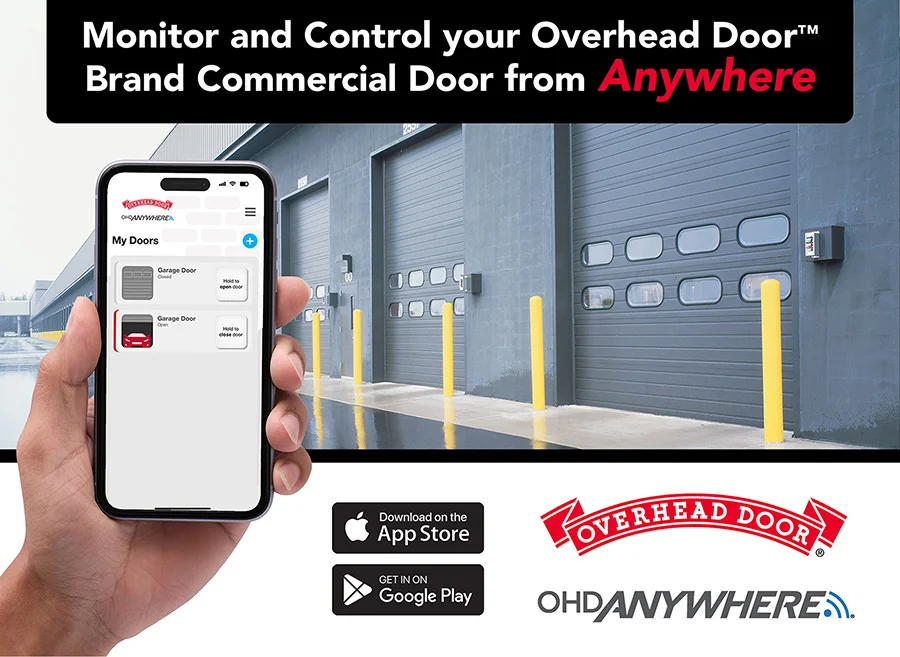 Hand holding smartphone displaying Overhead Door™ app interface for monitoring commercial garage doors, featuring industrial garage doors in the background, emphasizing remote control capabilities.