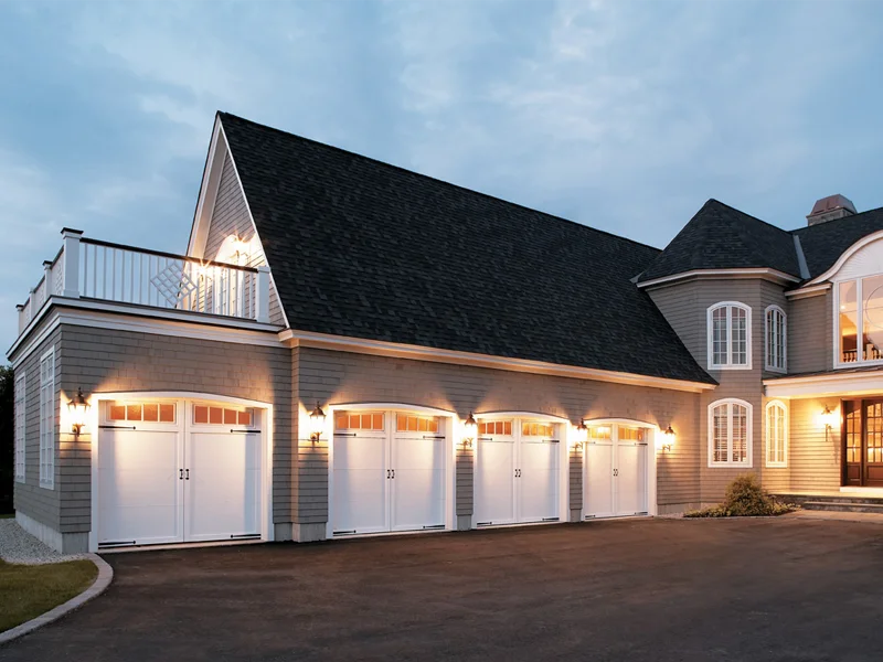 Stylish residential garage doors illuminated at dusk, enhancing curb appeal and security, showcasing Overhead Door Company of The Desert™'s quality installation services.