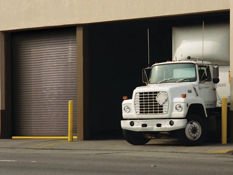 Truck trailer parked in front of a commercial roll-up door, highlighting Overhead Door Company of The Desert's services for efficient cargo handling and fleet operations.